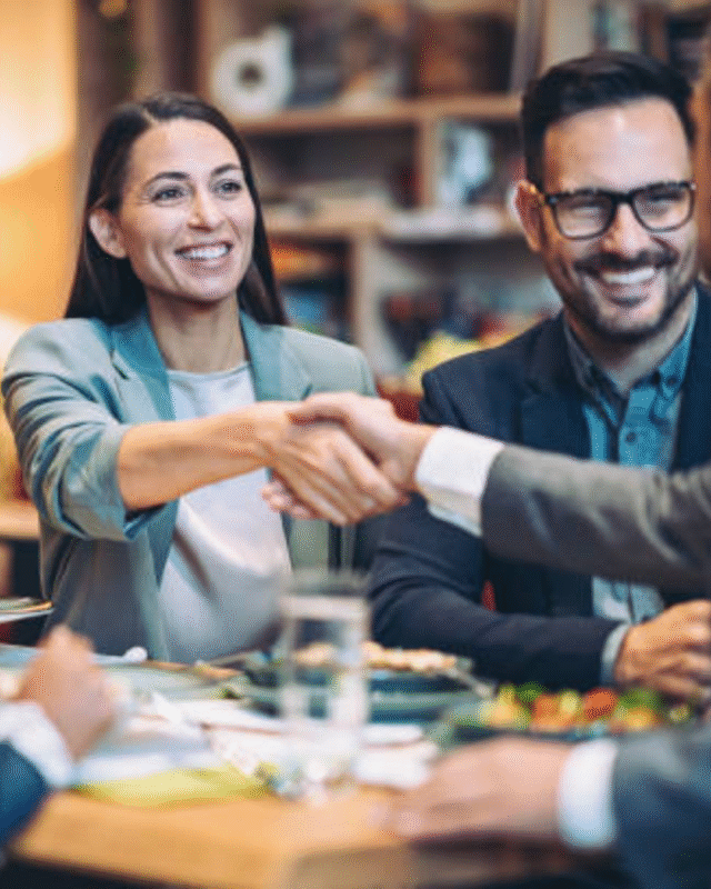 Professionals shaking hands at a lunch table