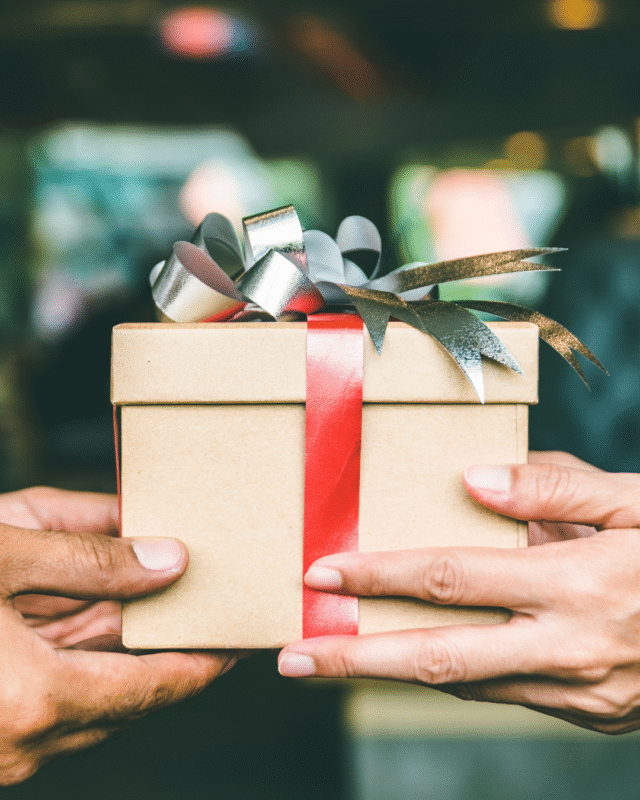 A gift being handed between two sets of hands.