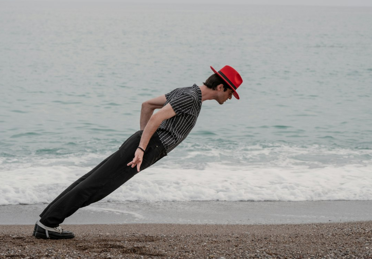 mime leaning on a beach with a red hat