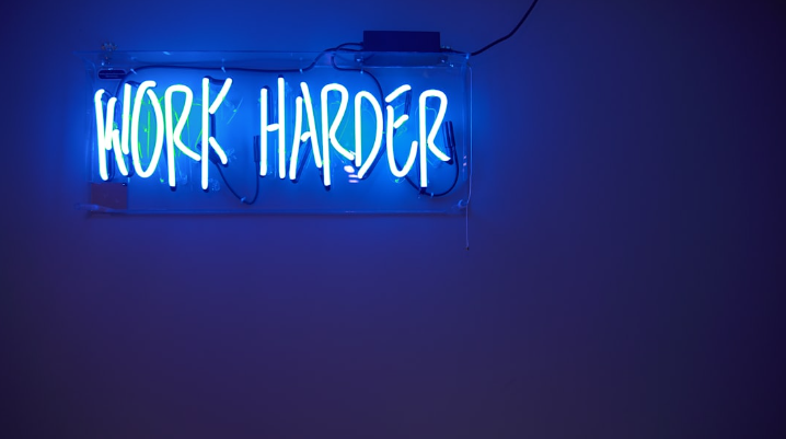 neon sign reading "work harder"